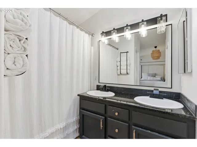 a bathroom with a granite countertop sink a mirror a and a shower curtain