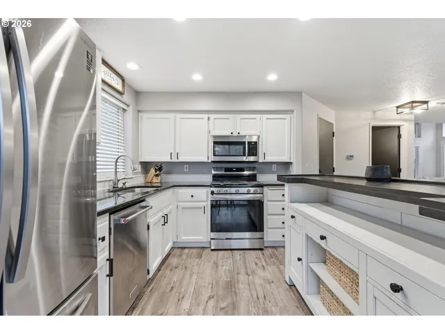 a kitchen with stainless steel appliances granite countertop a stove a sink and a refrigerator