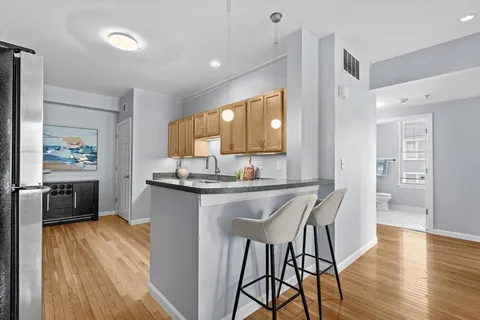 a kitchen with stainless steel appliances granite countertop a kitchen island hardwood floor sink stove dining table and chairs