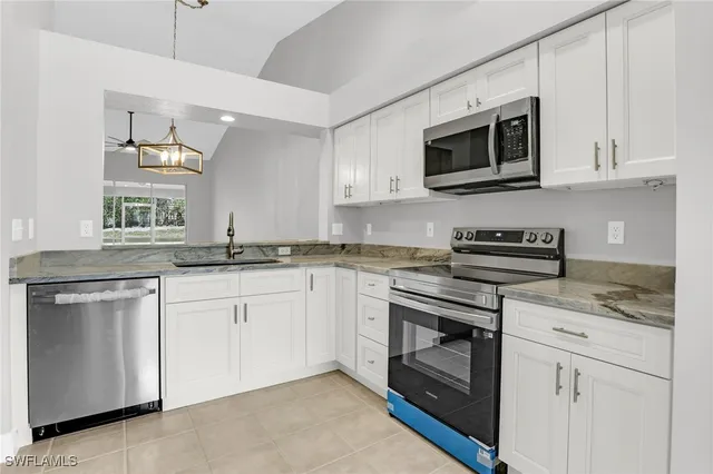 a kitchen with granite countertop white cabinets stainless steel appliances and a sink