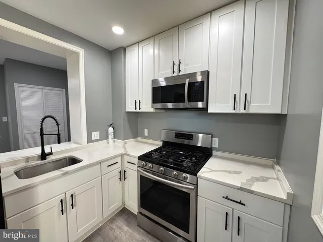 a kitchen with granite countertop white cabinets and stainless steel appliances