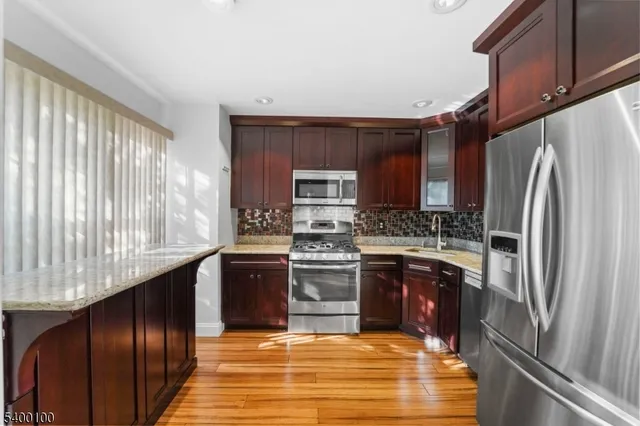a kitchen with stainless steel appliances granite countertop a refrigerator a stove and a sink