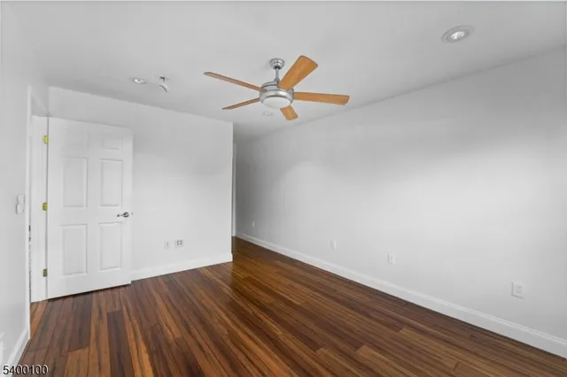 a view of room with wooden floor and a ceiling fan