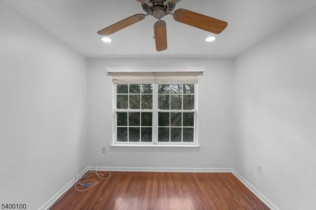an empty room with wooden floor fan and window