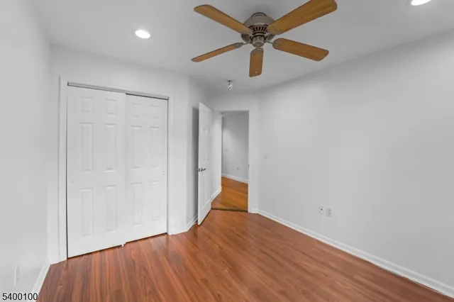 an empty room with wooden floor and a ceiling fan