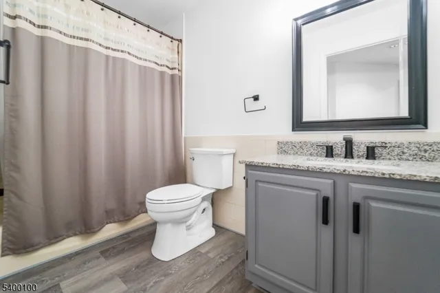 a bathroom with a granite countertop sink toilet and mirror