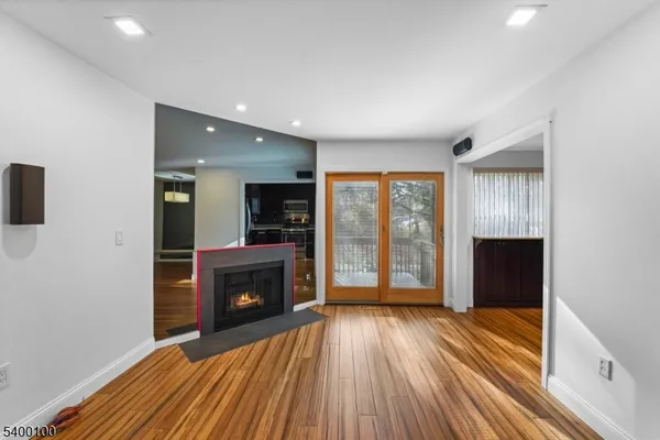 an empty room with wooden floor fireplace and windows