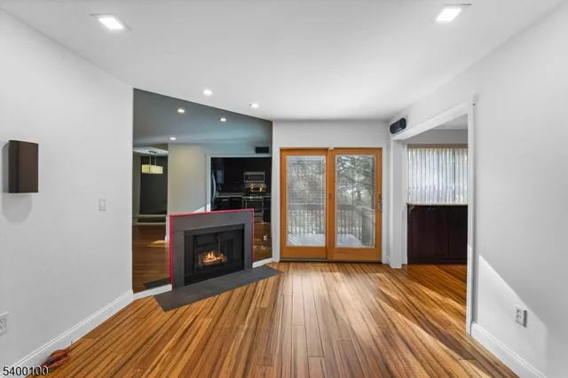 an empty room with wooden floor fireplace and windows