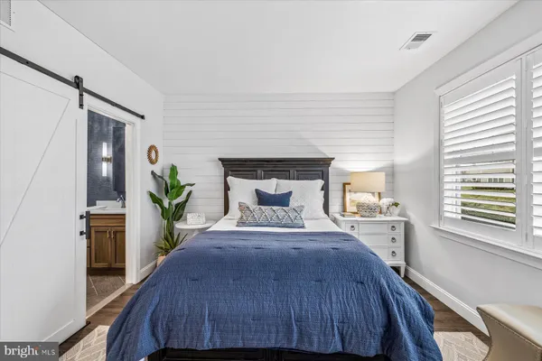 a bedroom with a bed and a potted plant on the dresser