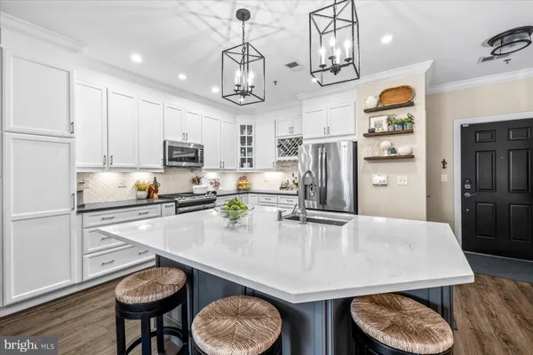 a kitchen with stainless steel appliances granite countertop a sink a stove a refrigerator cabinets and chairs