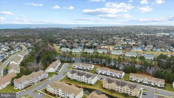 a front view of a building with lot of cars and trees