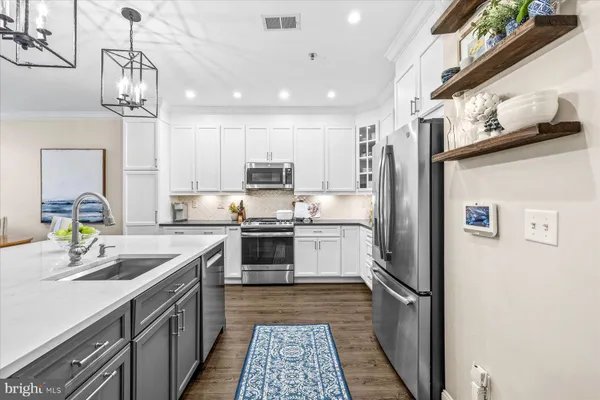 a kitchen with a sink stainless steel appliances and white cabinets