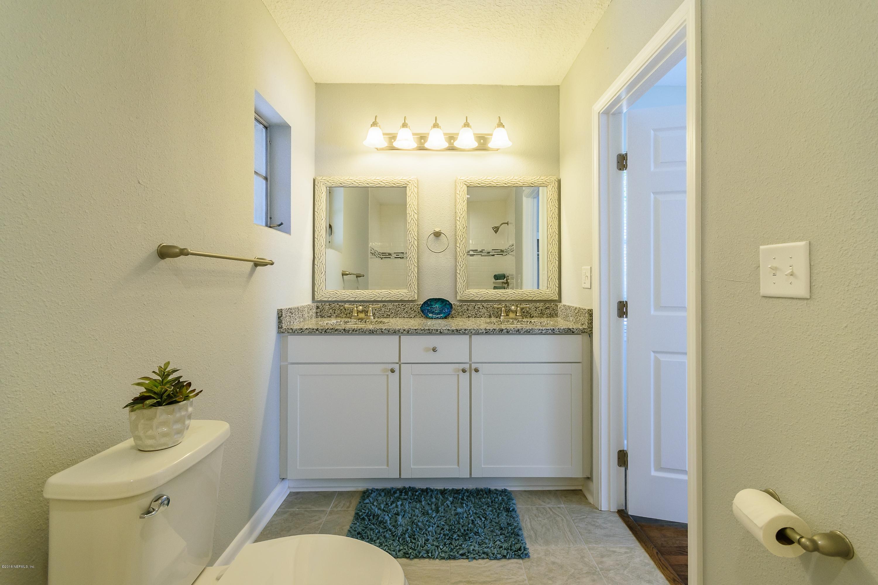 6330 Wesleyan Road Jacksonville, FL 32217 - Photo 11 of 17 a bathroom with a granite countertop sink a toilet a mirror and vanity