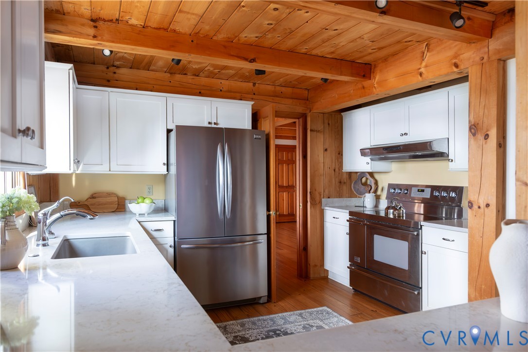 877 Twiggs Ferry Road Hartfield, VA 23071 - Photo 14 of 34 a kitchen with stainless steel appliances granite countertop a refrigerator a stove and a sink with wooden cabinets