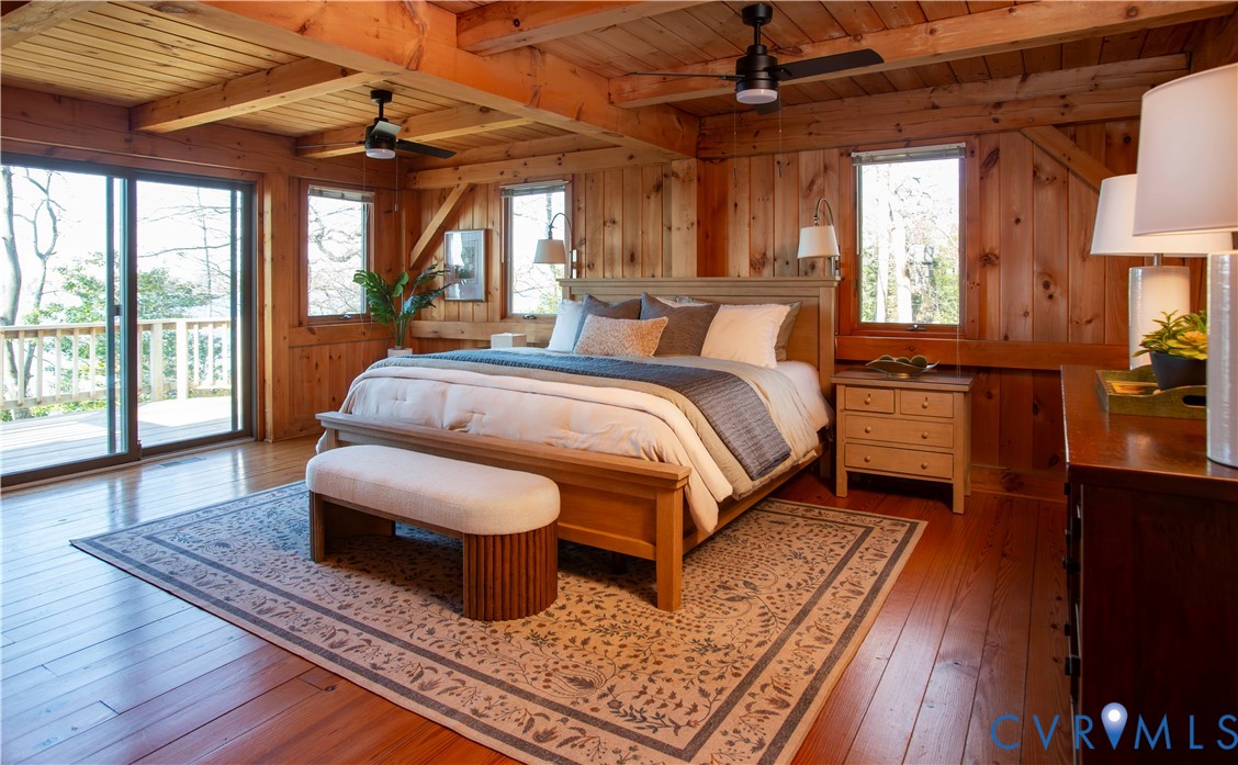 877 Twiggs Ferry Road Hartfield, VA 23071 - Photo 19 of 34 a spacious bedroom with a bed a chandelier and large window with wooden floor