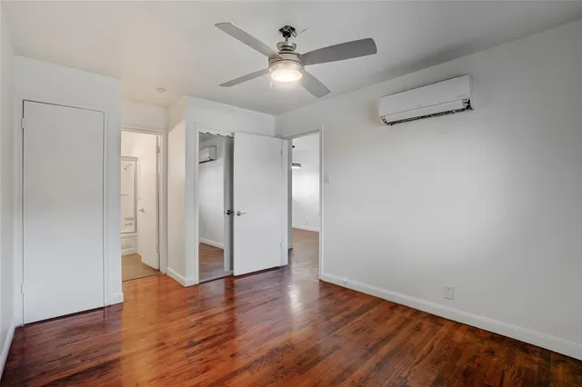 an empty room with wooden floor and a ceiling fan