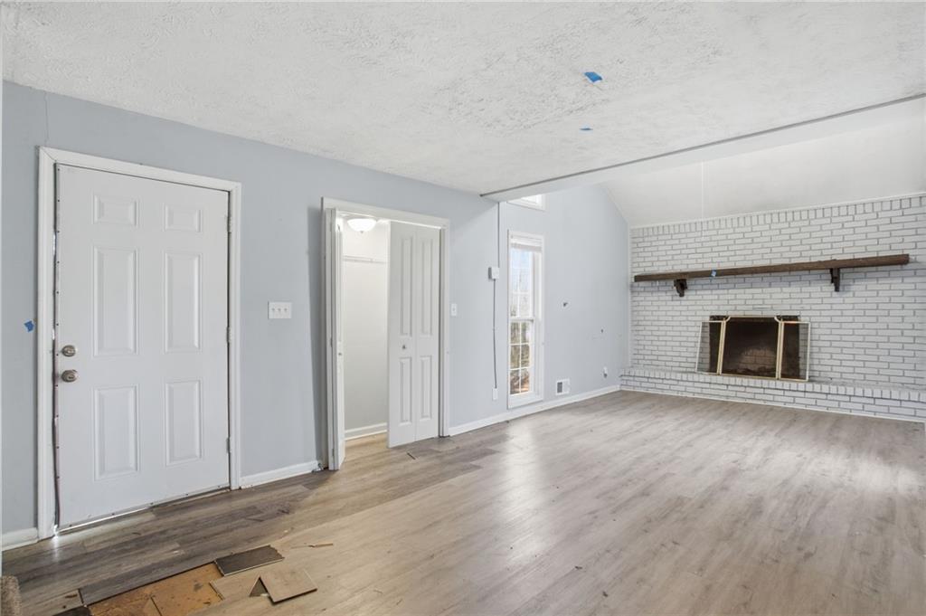 720 Twin Pines Road Covington, GA 30014 - Photo 14 of 40 an empty room with wooden floor and fireplace
