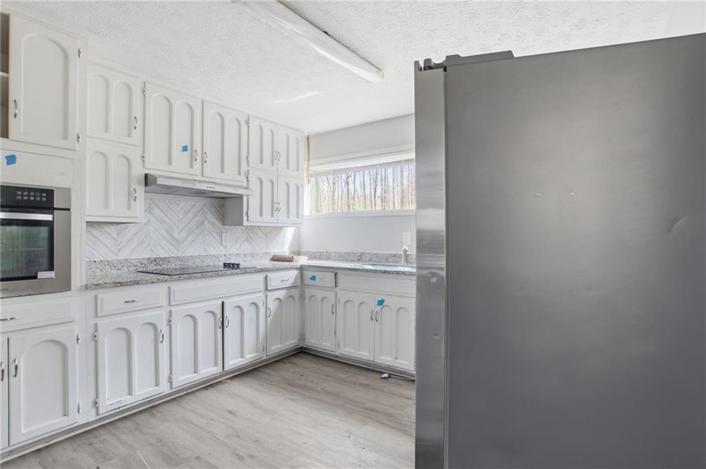 720 Twin Pines Road Covington, GA 30014 - Photo 17 of 40 a kitchen with granite countertop white cabinets white stainless steel appliances and sink
