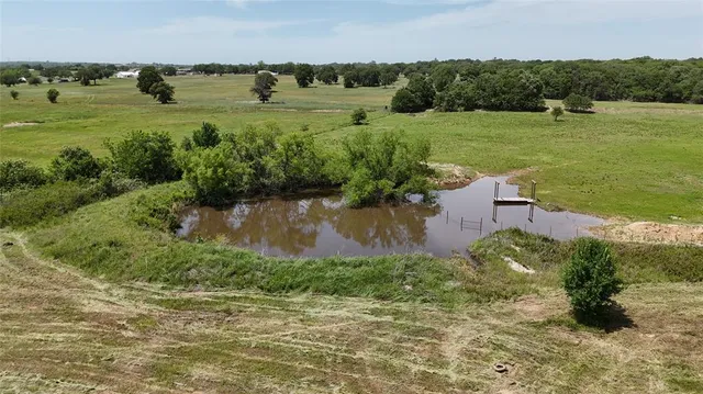 an aerial view of a houses with outdoor space and trees all around