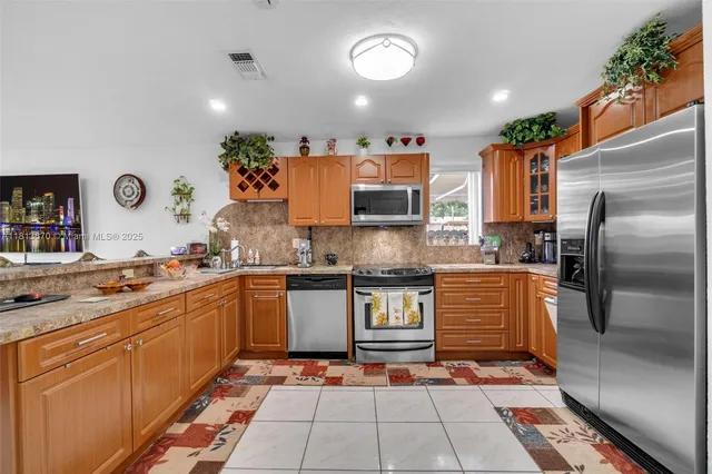 a large kitchen with stainless steel appliances granite countertop a stove a sink dishwasher and a refrigerator