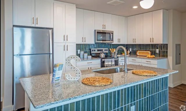 a kitchen with stainless steel appliances granite countertop a sink and a refrigerator