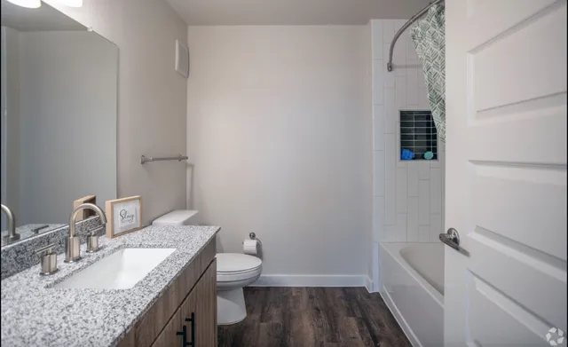 a bathroom with a granite countertop sink a toilet and a mirror
