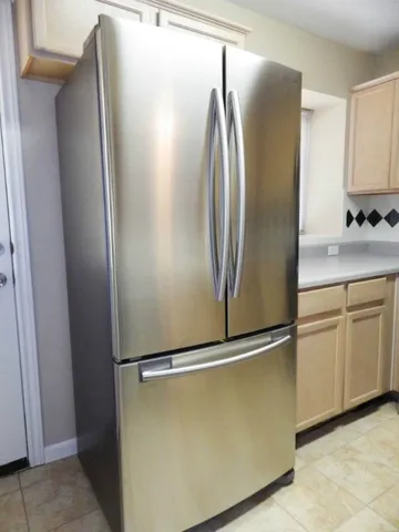a view of a refrigerator in kitchen and white cabinets