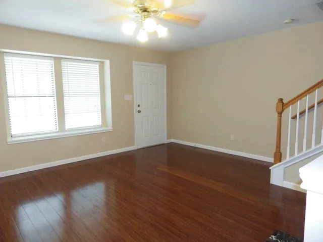 a view of an empty room with wooden floor and a window