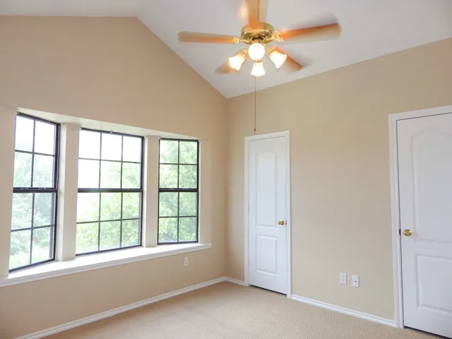 an empty room with windows and fan