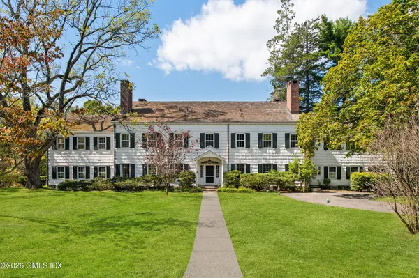 a front view of a house with a garden and trees