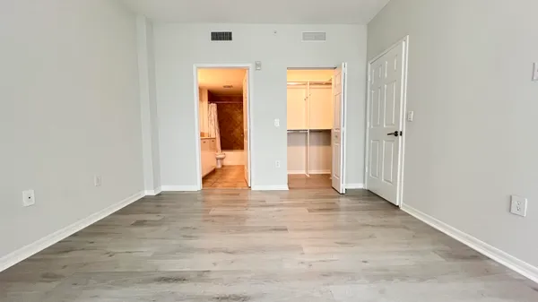 a view of an empty room with wooden floor and closet