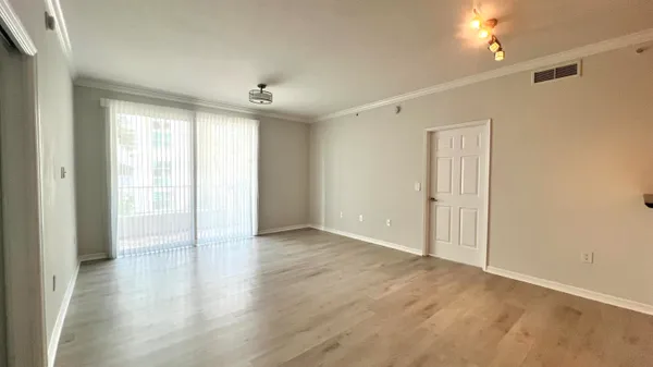 a view of an empty room with window and wooden floor
