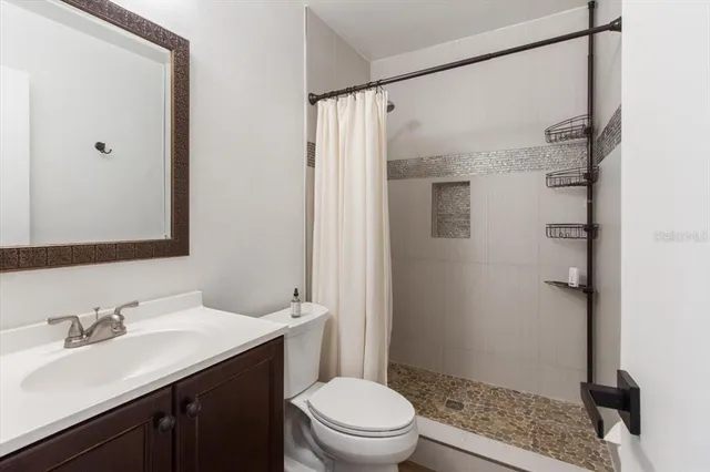 a bathroom with a sink a toilet a shower and a mirror
