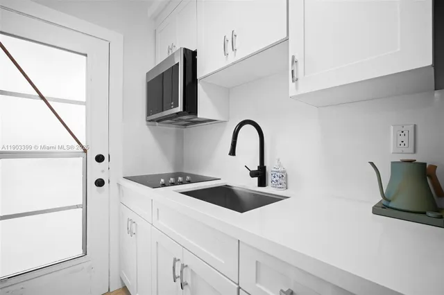 a kitchen with stainless steel appliances a microwave a sink and white cabinets