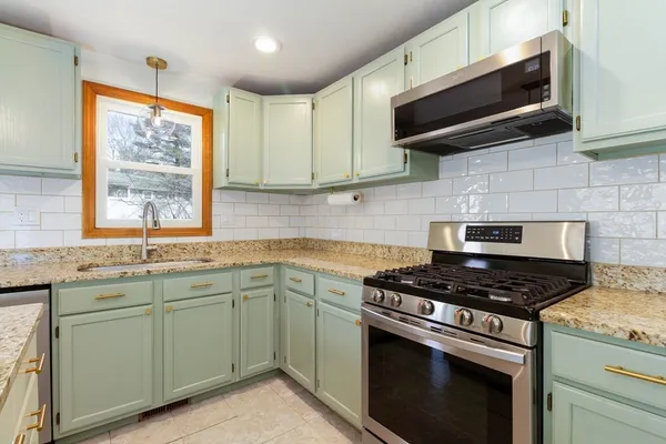 a kitchen with granite countertop cabinets stainless steel appliances and a window