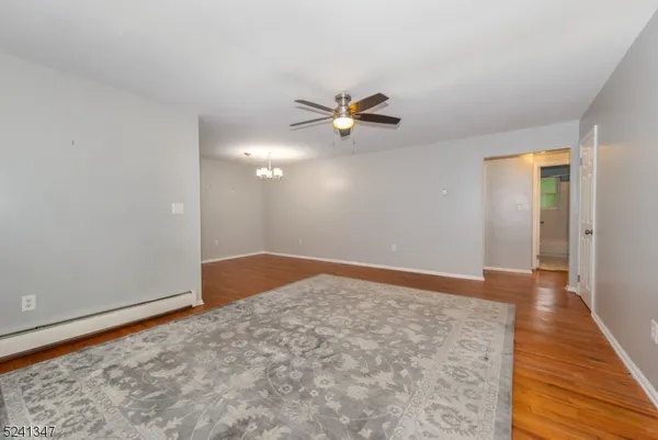 an empty room with wooden floor and fan
