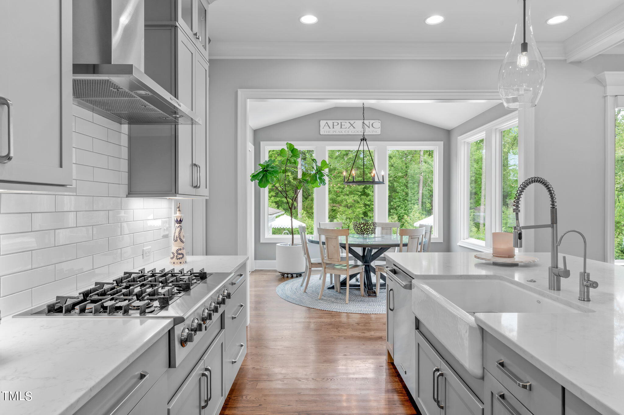 3130 Mantle Ridge Drive Apex, NC 27502 - Photo 21 of 81 a kitchen with stainless steel appliances a sink a stove top oven a dining table and chairs with wooden floor