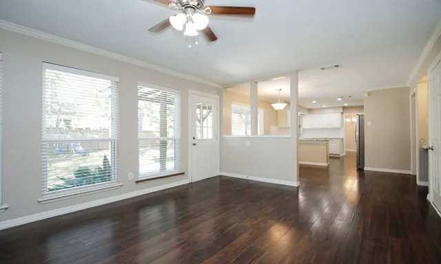 a view of an empty room with wooden floor and a window