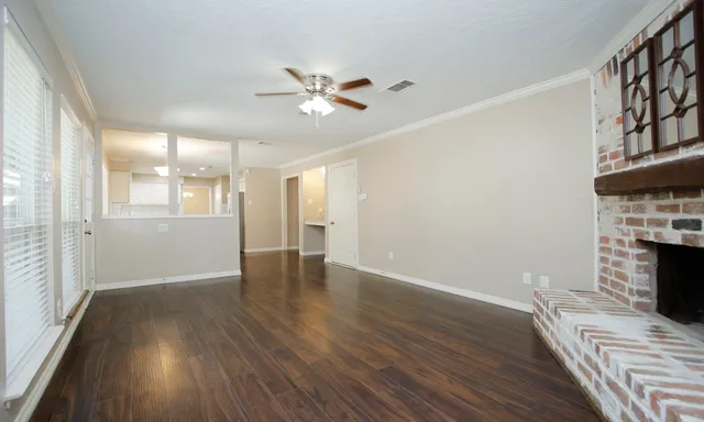 a view of an empty room with wooden floor fireplace and a window