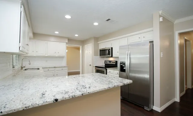 a kitchen with stainless steel appliances granite countertop a refrigerator a stove and a sink