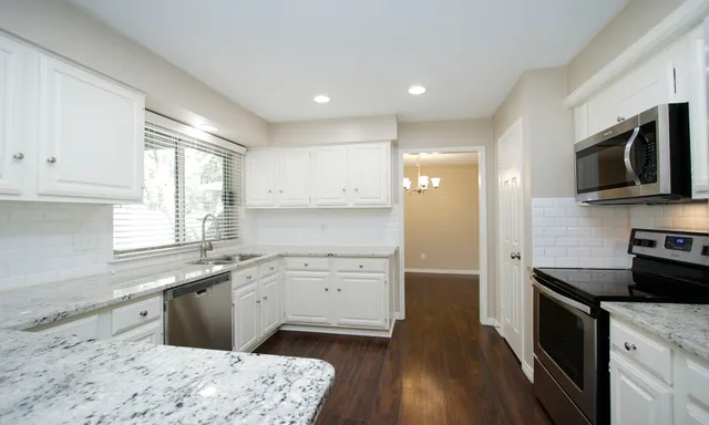 a kitchen with a sink wooden floor and stainless steel appliances
