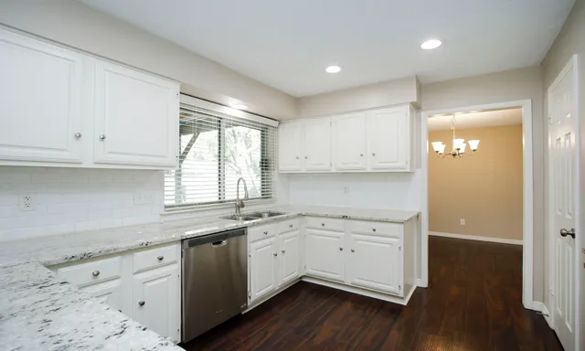 a kitchen with a sink cabinets wooden floor and a window