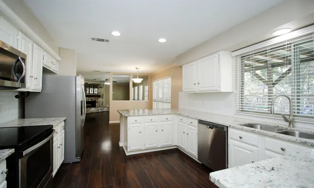 a kitchen with a sink wooden floor and stainless steel appliances