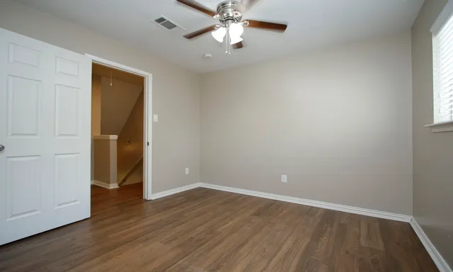 an empty room with wooden floor and windows