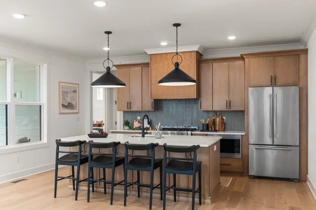 a kitchen with stainless steel appliances a dining table chairs refrigerator and cabinets