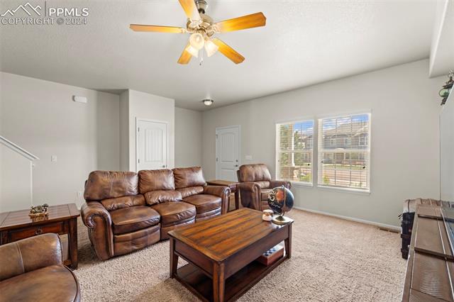 6310 Pilgrimage Road Colorado Springs, CO 80925 - Photo 8 of 31 Carpeted living room with ceiling fan and a textured ceiling