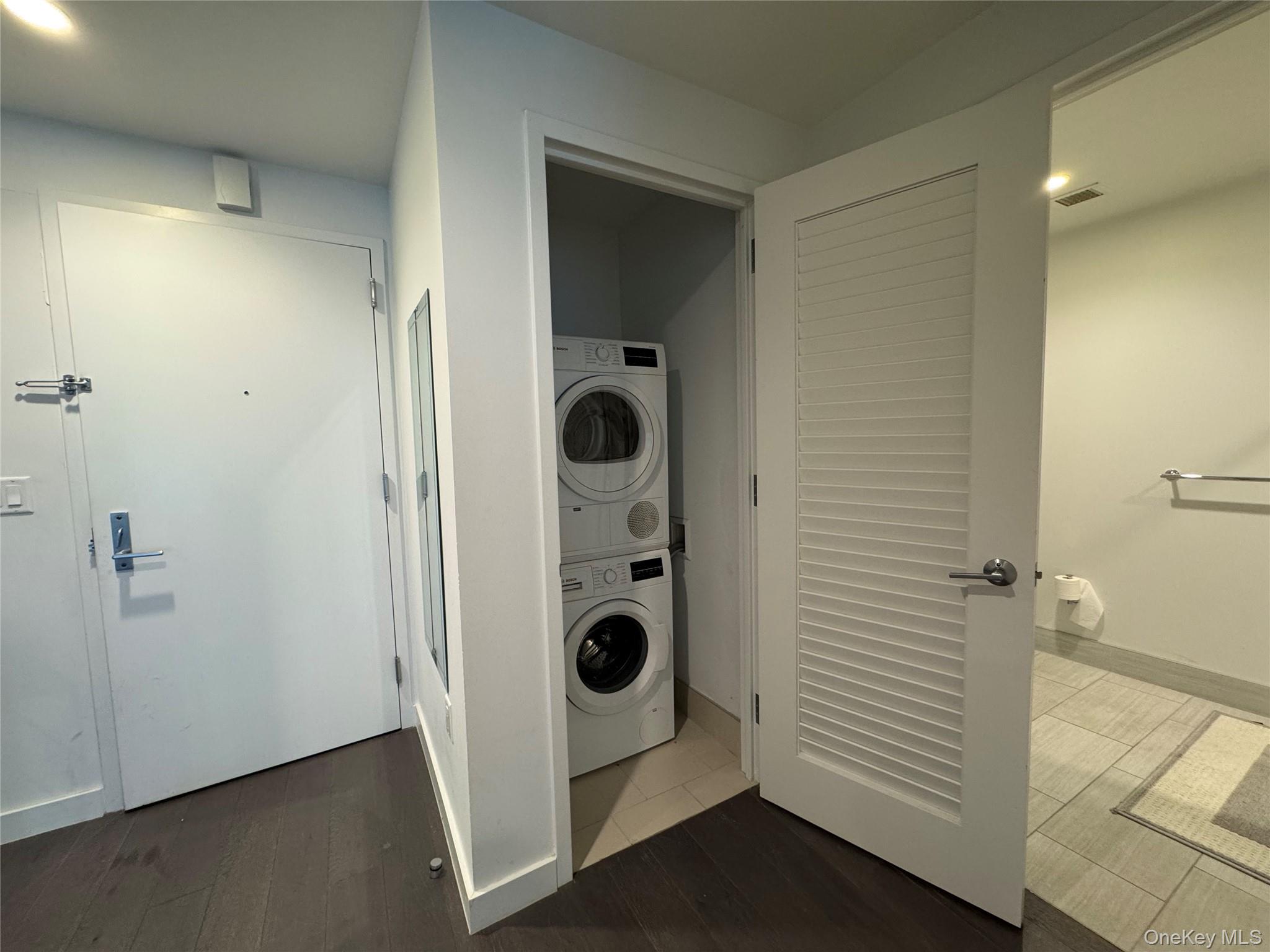 131-03 40 Road, Unit 10H Queens, NY 11354 - Photo 3 of 10 Washroom with stacked washer and clothes dryer and wood finished floors