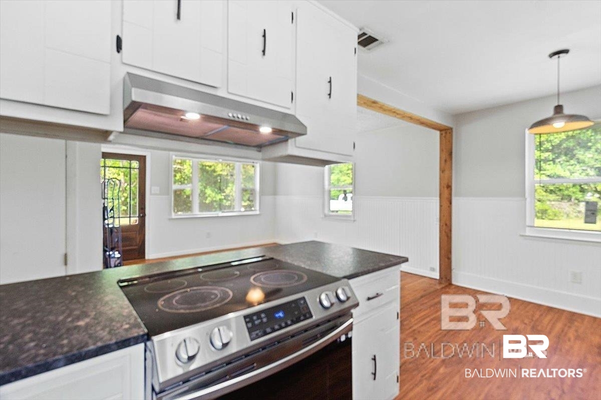 29397 Loper Road Loxley, AL 36551 - Photo 19 of 22 Kitchen with white cabinetry, stainless steel range with electric cooktop, a wainscoted wall, under cabinet range hood, and light wood-style floors