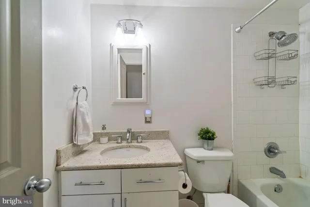 a bathroom with a granite countertop sink a toilet and shower