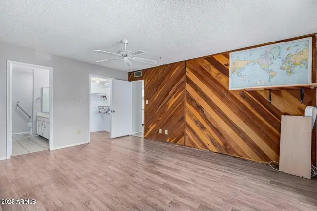 a view of an empty room with wooden floor and a ceiling fan